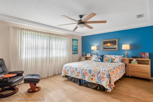 bedroom with ceiling fan, a textured ceiling, and light wood-type flooring