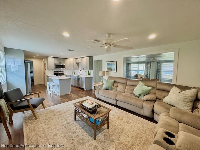 living room with hardwood / wood-style floors, ceiling fan, and sink