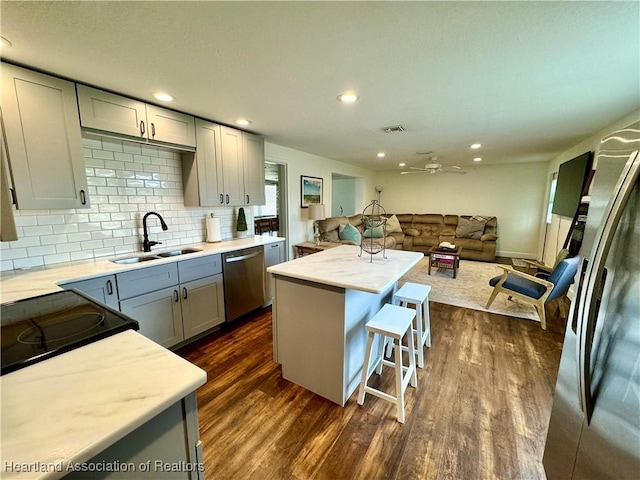 kitchen with gray cabinetry, sink, dark hardwood / wood-style floors, a kitchen island, and stainless steel appliances