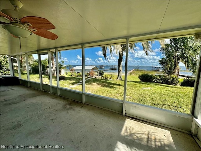 unfurnished sunroom with ceiling fan and a water view