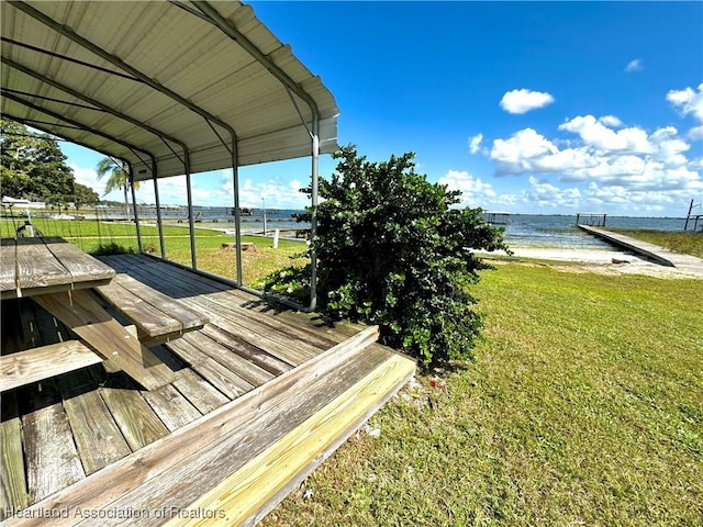 view of dock featuring a view of the beach, a yard, and a water view