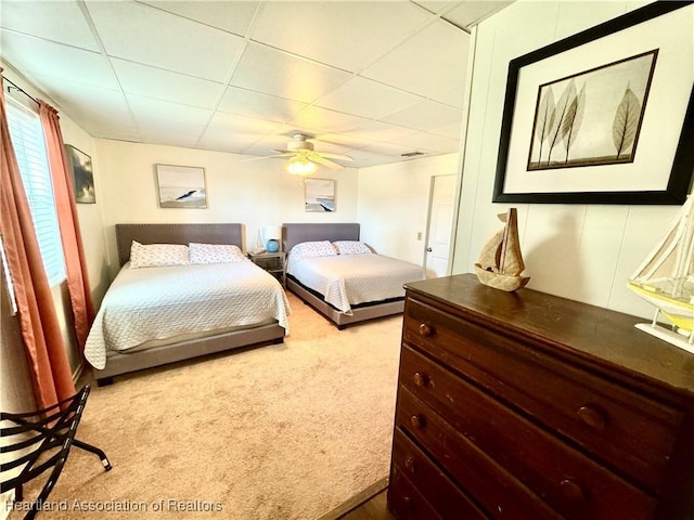 bedroom with ceiling fan, a drop ceiling, and light carpet