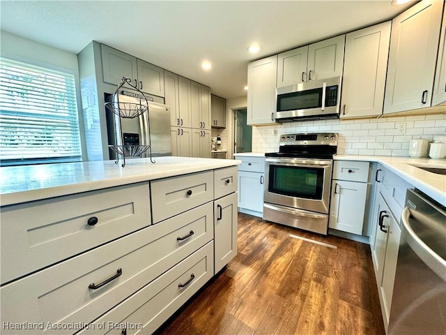 kitchen featuring white cabinets, decorative backsplash, dark wood-type flooring, and appliances with stainless steel finishes