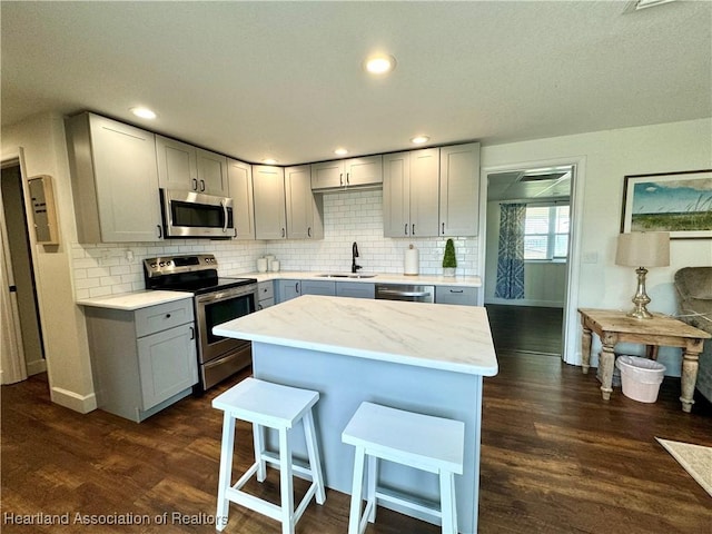 kitchen with gray cabinetry, sink, dark hardwood / wood-style flooring, and appliances with stainless steel finishes