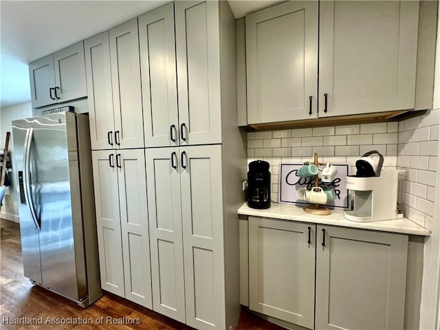 kitchen featuring tasteful backsplash, dark wood-type flooring, and stainless steel refrigerator with ice dispenser