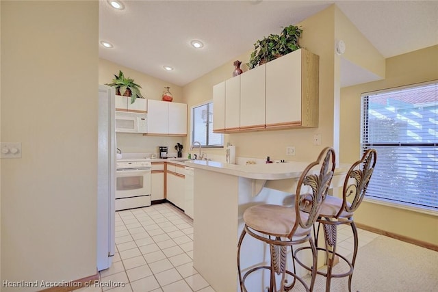 kitchen featuring kitchen peninsula, white appliances, sink, light tile patterned floors, and white cabinets