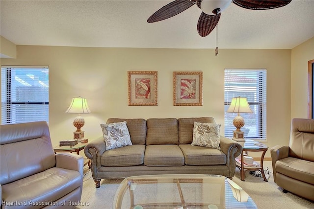 living room featuring ceiling fan, carpet floors, and a textured ceiling