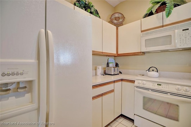 kitchen with white cabinets, light tile patterned flooring, and white appliances