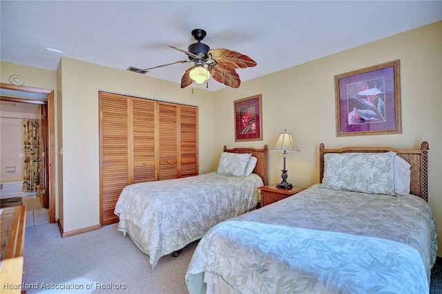 bedroom with a textured ceiling, ceiling fan, light carpet, and a closet