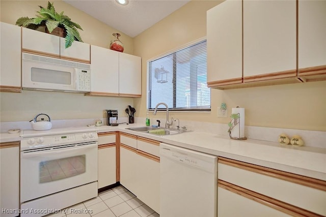 kitchen with sink, white cabinets, white appliances, and light tile patterned floors