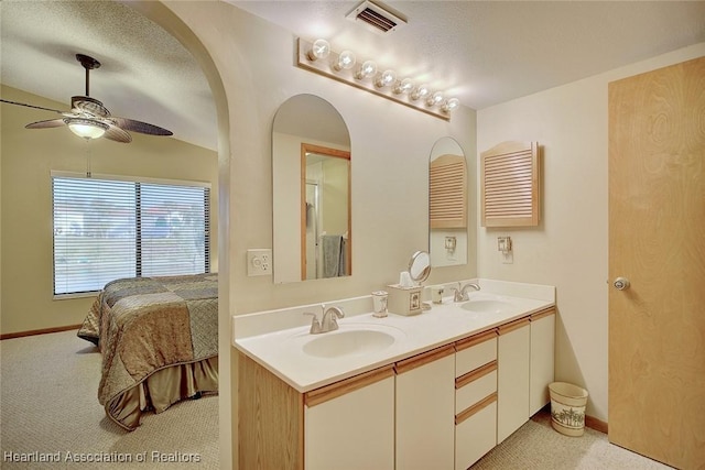 bathroom with ceiling fan, a textured ceiling, and vanity