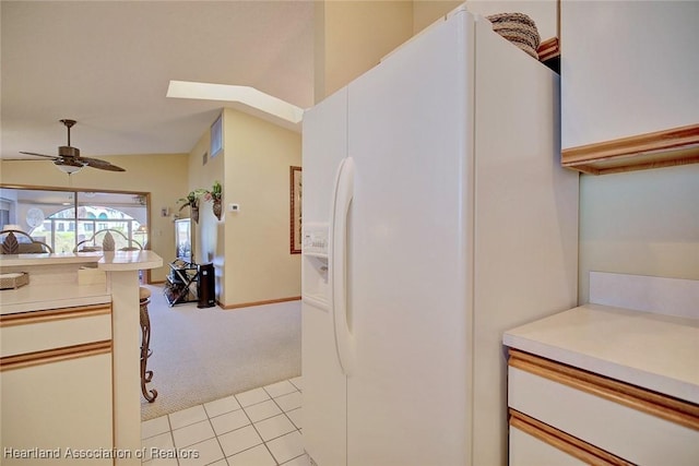 kitchen with light colored carpet, white cabinetry, white fridge with ice dispenser, and ceiling fan