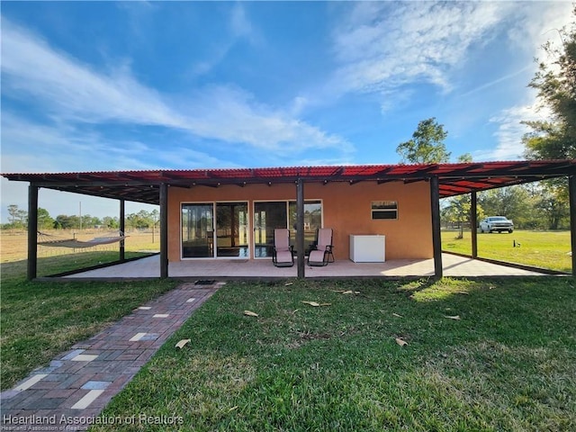 back of property featuring a patio area, a lawn, and stucco siding