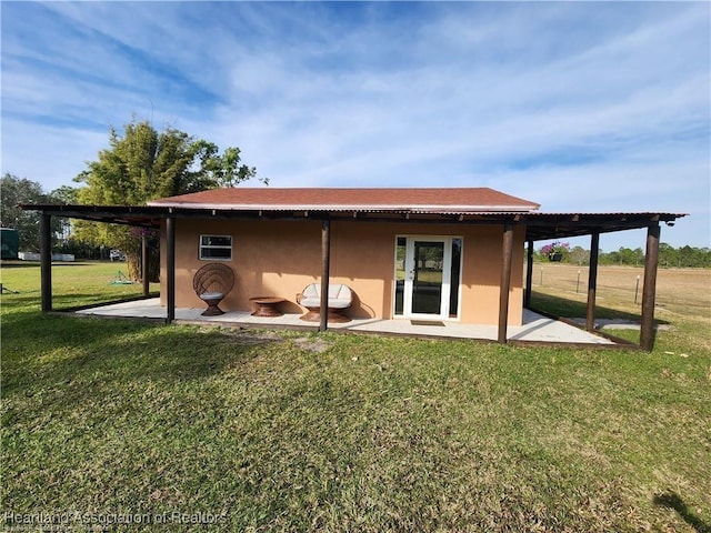 back of property with a patio, a lawn, and stucco siding