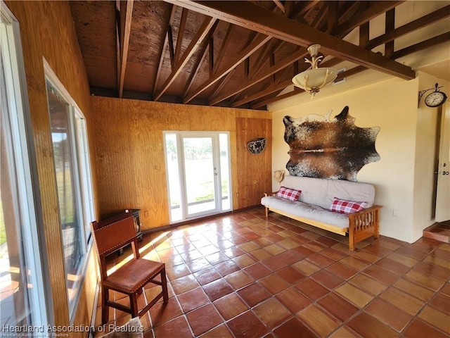 interior space with dark tile patterned flooring, beam ceiling, and wooden walls