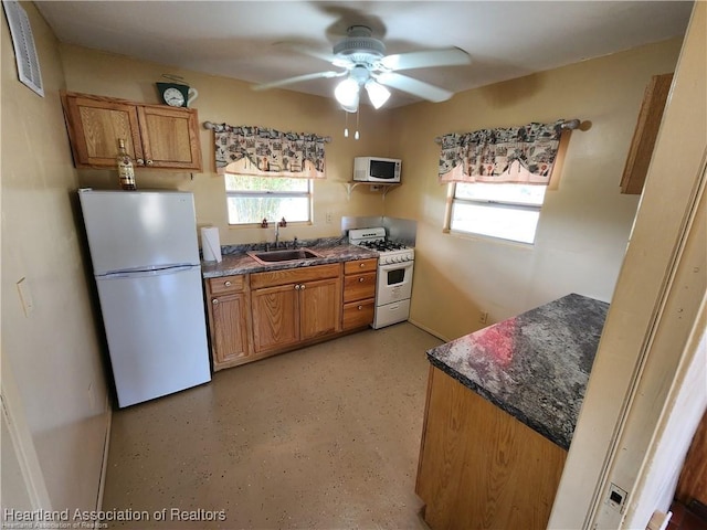 kitchen featuring white appliances, plenty of natural light, brown cabinets, and a sink