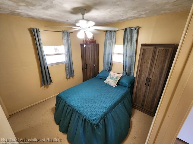 bedroom with concrete flooring, multiple windows, and baseboards