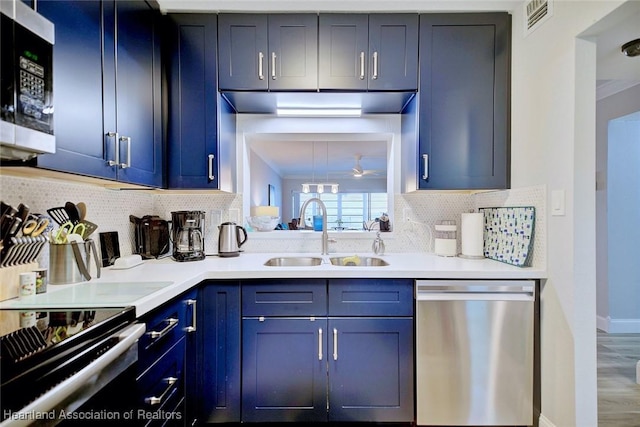 kitchen featuring tasteful backsplash, stainless steel appliances, light countertops, blue cabinetry, and a sink