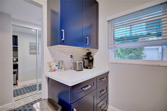 bar featuring light wood-type flooring, backsplash, and baseboards