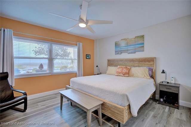 bedroom with a ceiling fan, multiple windows, baseboards, and wood finished floors