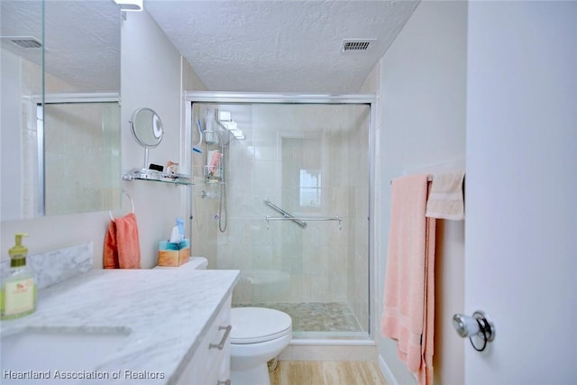 bathroom with a stall shower, visible vents, a textured ceiling, and toilet