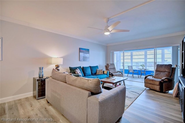 living area featuring ornamental molding, baseboards, light wood finished floors, and a ceiling fan