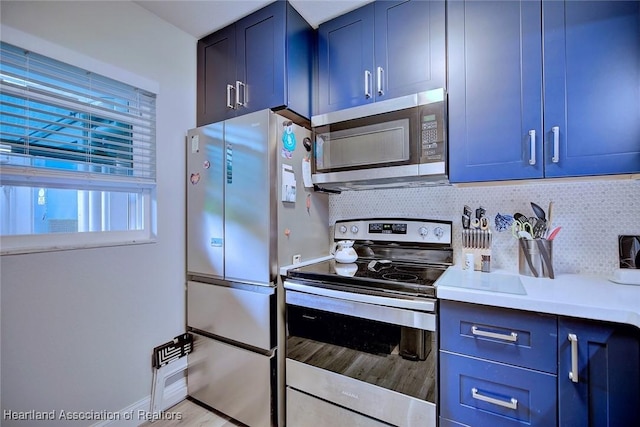 kitchen with stainless steel appliances, light countertops, blue cabinets, and tasteful backsplash