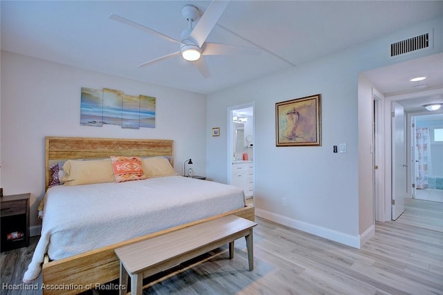 bedroom with light wood-style floors, visible vents, baseboards, and ensuite bathroom