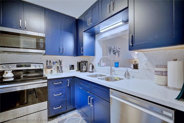 kitchen featuring appliances with stainless steel finishes, blue cabinets, a sink, light countertops, and backsplash