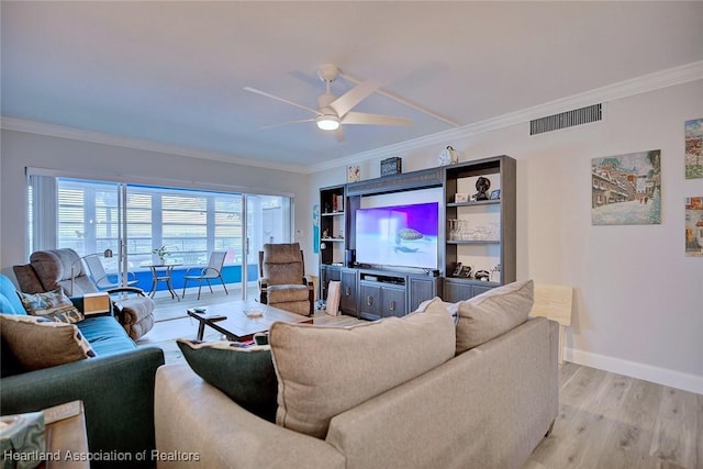 living room featuring light wood-style floors, baseboards, visible vents, and crown molding