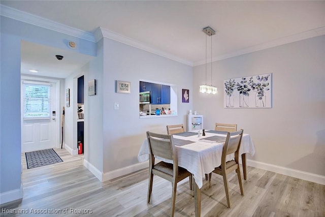 dining room featuring light wood-style flooring, baseboards, and ornamental molding
