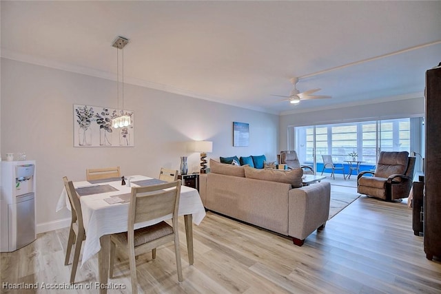 living room with baseboards, ornamental molding, ceiling fan with notable chandelier, and light wood-style floors