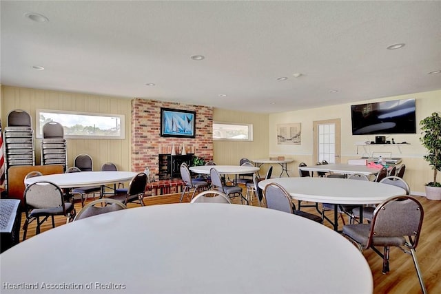 dining area featuring a brick fireplace, wood finished floors, and recessed lighting