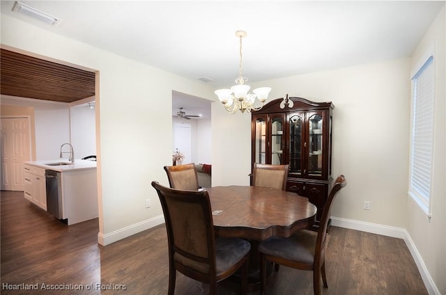 dining space with sink, ceiling fan with notable chandelier, and dark hardwood / wood-style floors