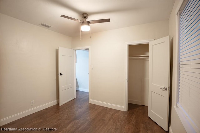 unfurnished bedroom with ceiling fan, dark wood-type flooring, and a closet