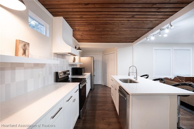 kitchen with a kitchen bar, appliances with stainless steel finishes, custom exhaust hood, sink, and white cabinetry