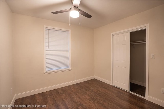 unfurnished bedroom featuring dark hardwood / wood-style flooring, ceiling fan, and a closet