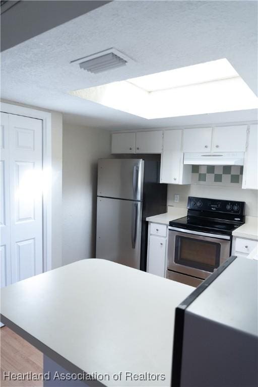 kitchen with a textured ceiling, light wood-type flooring, white cabinetry, and stainless steel appliances