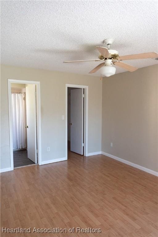 empty room with ceiling fan, wood-type flooring, and a textured ceiling