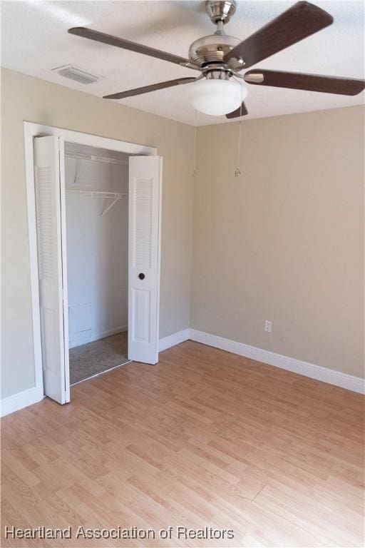 unfurnished bedroom with a closet, light hardwood / wood-style flooring, and ceiling fan