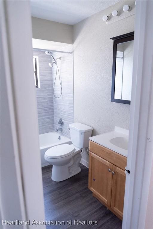 full bathroom featuring hardwood / wood-style flooring, vanity, toilet, and tiled shower / bath