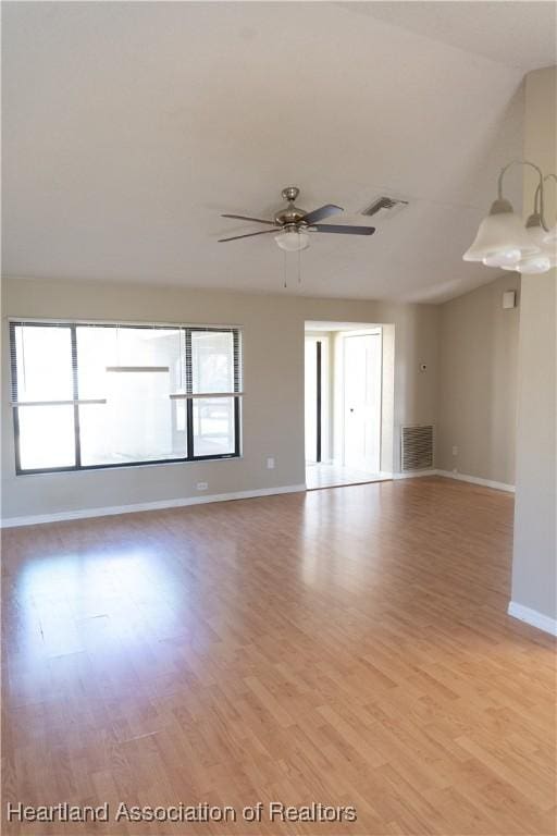 spare room featuring ceiling fan with notable chandelier and light wood-type flooring