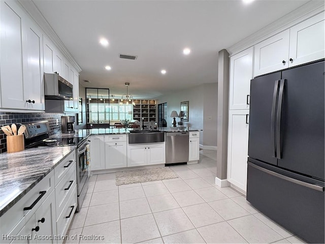 kitchen featuring appliances with stainless steel finishes, white cabinets, a sink, and backsplash