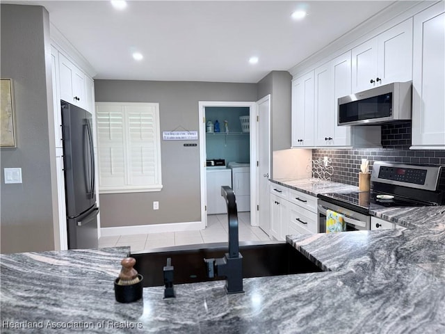 kitchen featuring white cabinetry, stainless steel appliances, and dark stone countertops