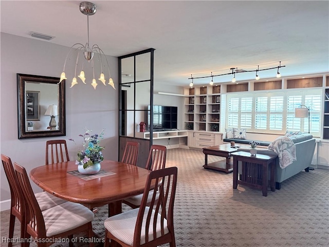 dining area featuring a notable chandelier, rail lighting, visible vents, and light colored carpet