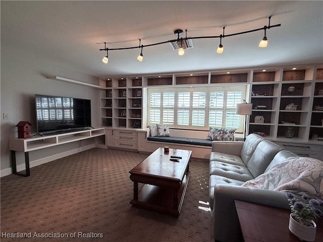 living area featuring rail lighting, dark carpet, and baseboards