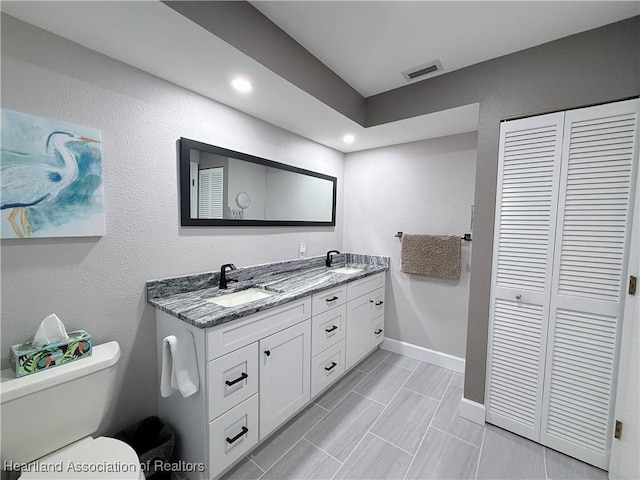 full bath featuring a sink, double vanity, visible vents, and a closet