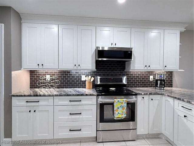 kitchen featuring dark stone counters, appliances with stainless steel finishes, white cabinetry, and decorative backsplash