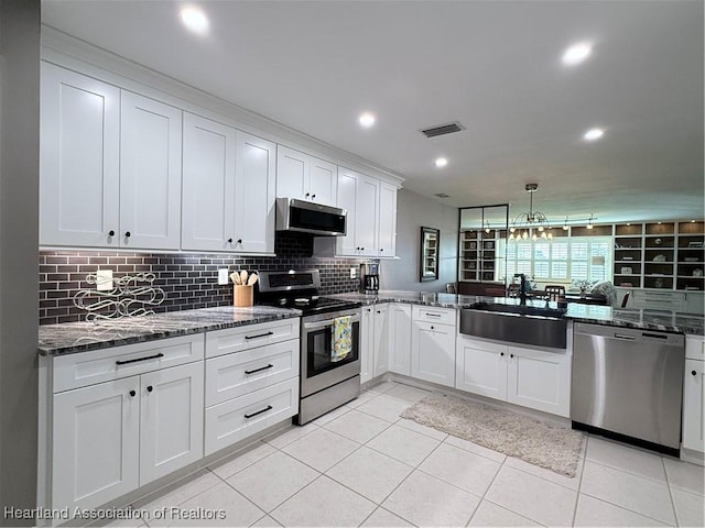 kitchen featuring a sink, visible vents, white cabinets, appliances with stainless steel finishes, and dark stone counters