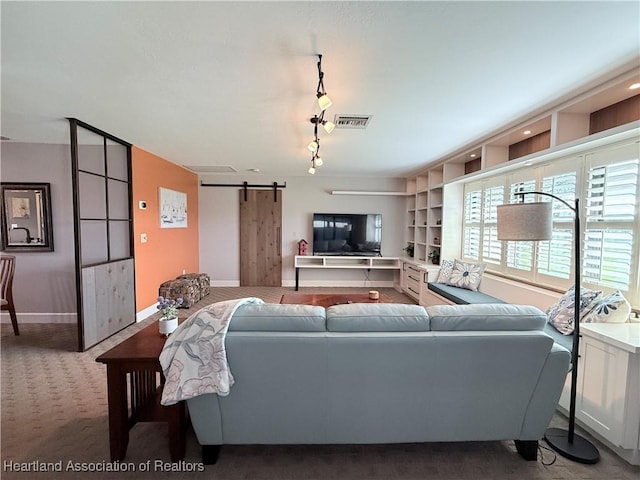 living room with a barn door, visible vents, baseboards, carpet, and track lighting